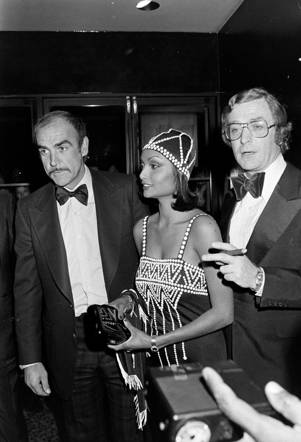 “Sean Connery, Shakira Caine, and Michael Caine Attending a Film Screening, 1975”